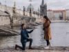 Where to Propose in Prague: 15 Best Spots and When to Go A man kneels to propose to a surprised woman on the Vltava embankment by Charles Bridge in Prague