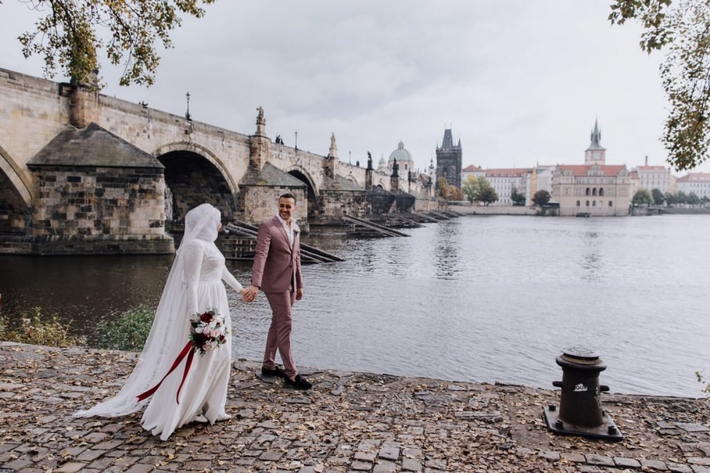 Wedding couple walking on Charles Bridge in Prague
